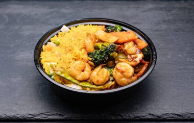 Sebzeli kızarmış karides ve siyah kasede pilav.