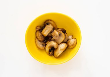 Beyaz arka planda sarı bir fincanda kızarmış mantar.