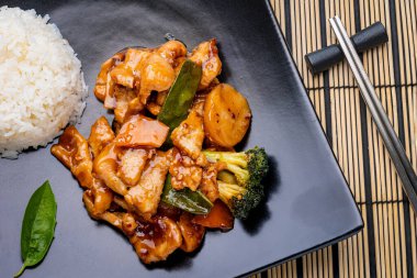 Siyah tabakta sebzeli tavuk pilavı.