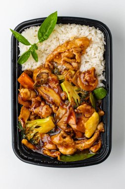 Tavuklu pilav, kızartma, sebze ve tavuk siyah kabın içinde.