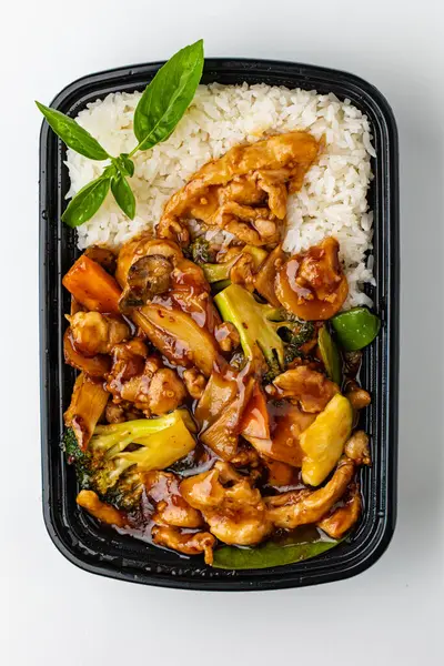 Tavuklu pilav, kızartma, sebze ve tavuk siyah kabın içinde.