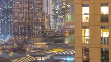 Dünya saatinde Dubai 'de, Birleşik Arap Emirlikleri' nde gece balkonlarında restoranlarla alışveriş merkezleri açılır. Arka planında en yüksek gökdelen olan gökyüzü manzarası. Işıklar yanıyor.