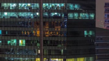 Modern ofis binalarında gece aydınlatmalı pencereler zaman ayarlı. Parlayan ışıkları olan çok katlı gökdelenler..