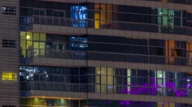Pencereler gece aydınlatmalı modern cam bina zaman ayarlı. Parlayan ışıkları olan çok katlı gökdelenler..