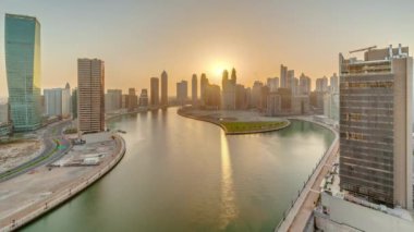 Dubai İş Körfezi 'ndeki gökdelenlerin günbatımında su kanalı panoramik zaman dilimi. Kuleleri ve limanı olan modern gökyüzü. Uluslararası bir iş merkezi.