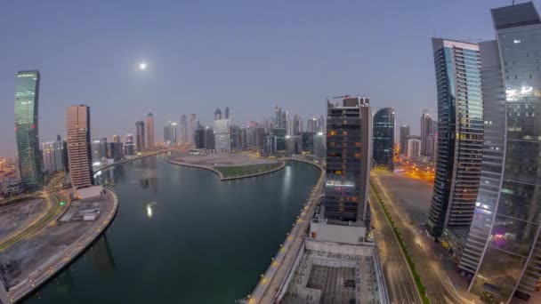 迪拜商业湾摩天大楼的全景全景 随着月亮落山 经过了一条运河的空中通宵的过渡时间 有照明塔和海滨的现代天际线 — 图库视频影像