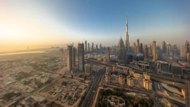 Dubai şehir merkezindeki en yüksek kulelerin panoramik hava manzarası ve karayolu zaman çizelgesi. Gündoğumunda akıllı kentlerdeki finans bölgesi ve iş sahası