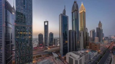 Dubai Uluslararası Finansal Bölgesi 'nin hava manzarası. Gün batımından sonra birçok gökdelen ve gece geçiş zamanı var. Çatı yüzme havuzlu çok katlı otoparkın yakınındaki bir yolda trafik vardı.