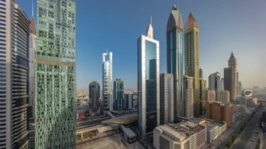 Dubai Uluslararası Finans Bölgesi 'nin hava panoramik görüntüsü. Gün boyunca birçok gökdelen zaman dilimi var. Çok katlı otoparkın yakınındaki yolda trafik vardı. Gölgeler hızla ilerliyordu. Dubai, BAE.