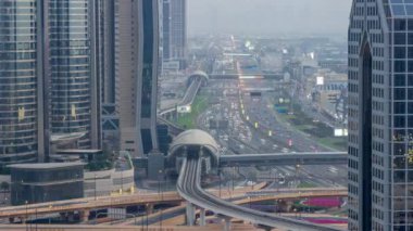 Şeyh Zayed Yolu 'nun yoğun hava durumu günden geceye geçiş zamanı, metro yolu ve lüks Dubai şehrindeki modern gökdelenler. Otobanda bir sürü araba var. Birleşik Arap Emirlikleri