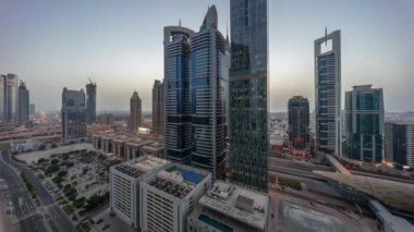 Dubai Uluslararası Finans Bölgesi 'nin hava manzarası. Gün batımından sonra gece gündüz aydınlık gökdelenlerle geçiş zamanı. Otoparkın yanındaki kavşakta trafik vardı. Dubai, BAE.