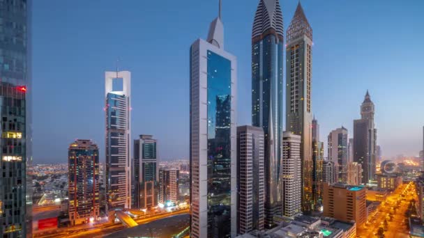迪拜国际金融区的空中景观与许多摩天大楼夜以继日的过渡时间过去了 地铁车站附近的道路和设有天台游泳池的多层停车场的交通情况 — 图库视频影像