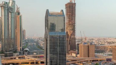 Dubai şehrinin ufuk çizgisi panoramik manzaralı metro ve araçlar şehrin en işlek otoban sabah saatlerinde hareket ediyor. Gün doğmadan önce uzun gölgelerle çevrili bir kavşak.