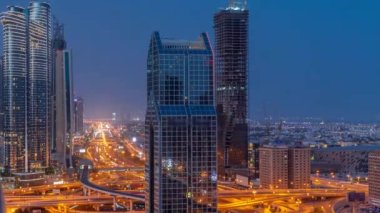 Dubai şehrinin ufuk çizgisi panoramik manzarası metro ve arabalar şehirlerde en yoğun karayolu üzerinde gece gündüz geçiş zamanı. Gün doğmadan önce gökdelenlerle çevrili bir kavşak.