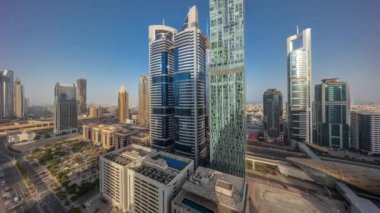 Dubai Uluslararası Finans Bölgesi 'nin panoraması. Gün doğumundan günbatımına kadar birçok gökdelen zaman çizelgesi var. Bütün gün boyunca çok katlı otoparkın yakınındaki bir yolda trafik vardı. Dubai, BAE.