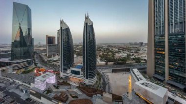 Günbatımından sonra Dubai Uluslararası Finansal Bölgesi 'nin havadan görünüşü ve birçok gökdelenin gece gündüz geçiş panoramik zamanlaması. Çatıda yürüme alanı olan alışveriş caddesi yakınındaki yollarda trafik vardı.