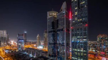 Dubai Uluslararası Finans Bölgesi 'nin tüm gece boyunca birçok gökdeleni olan hava manzarası. Işıkları sönmüş kulelerle çevrili bir otoyol kavşağında trafik vardı. Dubai