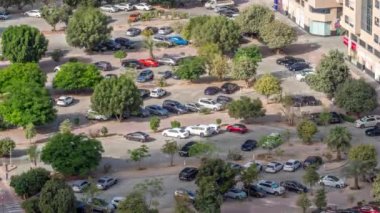 Otoparkta park halindeki sıra sıra yeşil yapraklı ağaçların arasına park edilmiş araçlar tüm gün boyunca yukarıdan izleniyor ve gölgeler hızla hareket ediyor. Dubai 'deki yerleşim bölgesinin havadan görüntüsü