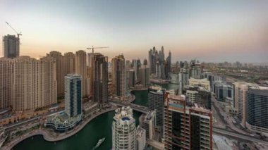 Dubai Marina hava sahasının en uzun bloğundaki çeşitli gökdelenlerin panoramasından gece gündüz yapay kanalla geçiş zamanına kadar. Günbatımından sonra JBR bölgesinde birçok kule ve yat var.