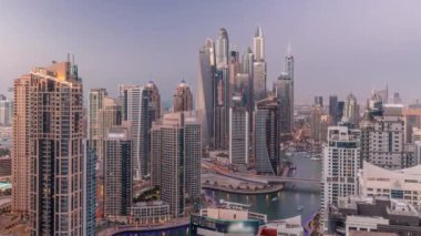 Dubai Marina hava sahasının en uzun bloğundaki çeşitli gökdelenlerin görüntüsü suni kanallı panoramik zaman geçişi. Gün batımından sonra birçok kule ve yat
