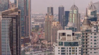 Dubai Marina ve Medya Şehri 'nin modern gökdelenleri ve ofis binaları ile hava gününden geceye geçiş zamanı. Yeşil park yakınlarındaki üst geçitte trafik ve kavşak.