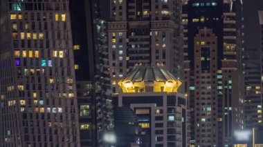 Parlak pencereli, dış apartman manzaralı bir zaman çizelgesi. Dubai marinasında ışıkları olan gökdelenler.