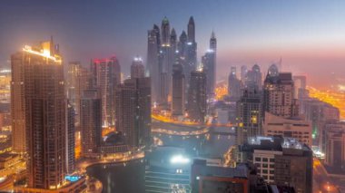 Dubai Marina hava sahasının en yüksek bloğundaki çeşitli gökdelenlerin görüntüsü. Gece gündüz yapay kanalla geçiş zamanı. Güneş doğmadan önce birçok kule ve yat sisli.