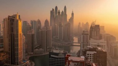 Sunrise Airial Timelapse sırasında Dubai Marina 'nın en yüksek karşılama bloğundaki yapay kanallı çeşitli gökdelenlerin görüntüsü. Birçok kule ve yat sisli sabahın erken saatlerinde