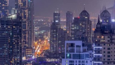 Dubai Marina ve Media City semtleri modern gökdelenler ve ofis binaları tüm gece boyunca antenli. Üstgeçitte trafik ve ışıkların kapandığı kavşak.