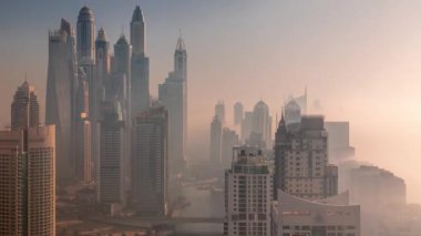 Sunrise Airial Timelapse sırasında Dubai Marina 'nın en yüksek karşılama bloğundaki yapay kanallı çeşitli gökdelenlerin görüntüsü. Birçok kule ve yat sabah sisi ile kaplandı.