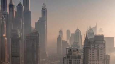 Sunrise Airial Timelapse sırasında Dubai Marina 'nın en yüksek karşılama bloğundaki yapay kanallı çeşitli gökdelenlerin görüntüsü. Birçok kule ve yat arasında sabah sisi
