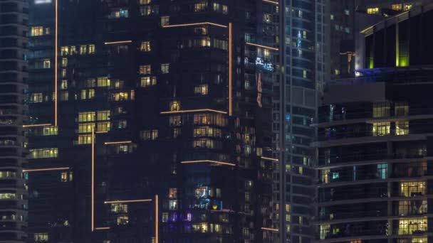 複数階建ての建物のパノラマウィンドウでの光の夜景空中タイムラプス 大都市にガラスの外壁を持つ照明付き超高層ビル — ストック動画
