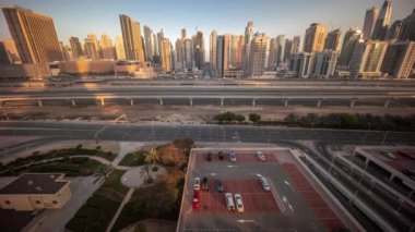 Dubai Marina gökdelenleri ve Şeyh Zayed yolu ile metro demiryolu sabah saatleri. Gündoğumu sırasında modern kulelerin yakınındaki bir otoyol trafiğine tepeden bakan panoramik, Birleşik Arap Emirlikleri