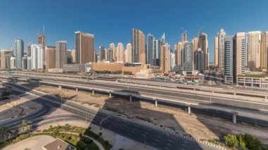 Panorama, Dubai Marina gökdelenlerini ve Şeyh Zayed yolunu metro demiryolu zaman çizelgesiyle gösteriyor. Modern kulelerin yakınındaki bir otoyolda trafik var, Birleşik Arap Emirlikleri