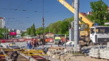 Yol inşaatı zamanına vinçle beton plakalar ve raylar yerleştiriliyor. Şapkalı ve üniformalı endüstriyel işçiler. Şehir caddesindeki tramvay raylarının yeniden inşası