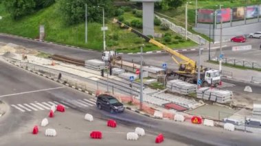 Büyük boy kamyondan beton plakaları yüklemek ve indirmek için vinç, uzun bir yükleme platformuyla birlikte, bir yol inşaatı alanının hava zaman tünelinde duruyor.