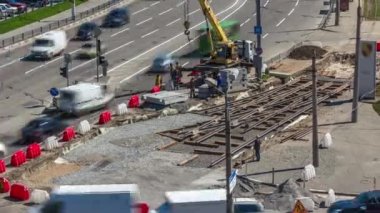 Yol inşaatı alanındaki hava zaman ayarına vinçle beton plakalar yerleştiriliyor. Şapkalı ve üniformalı endüstriyel işçiler. Şehir caddesindeki tramvay raylarının yeniden inşası