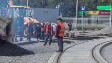 Asfalt paten ve buldozer asfaltlama sırasında yol onarım sahasında. Kamyon asfaltı ezilmiş taşa boşaltıyor. Tramvay izleri yeniden inşa ediliyor. Yol onarımı yapan inşaat işçileri.