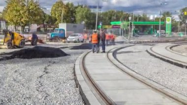 Asfalt patinaj ve buldozer asfalt zaman aşımı sırasında yol onarım alanında asfaltı hareket ettirir. Yol onarımı yapan inşaat işçileri. Tramvay izleri yeniden inşa ediliyor. Yol yapım ekipmanları.