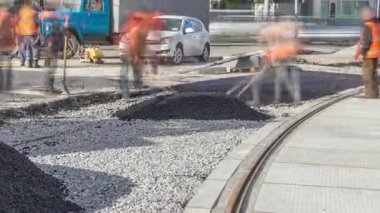 Buldozer asfaltlama sırasında yol onarım alanında asfalt hareket ettiriyor. Yol onarımı yapan inşaat işçileri. Tramvay izleri yeniden inşa ediliyor. Yol yapım ekipmanları.