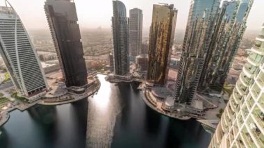 Gün doğumunda Dubai çok amaçlı emtia merkezi karma kullanım bölgesinin bir parçası olan JLT bölgesi hava zaman diliminde uzun konut binaları. Göldeki bir sudan yansıyan güneş.