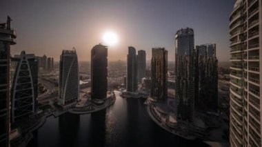 Tüm gün boyunca, Dubai 'nin karma kullanım merkezinin bir parçası olan JLT bölgesi hava zaman tünelinde bulunan yüksek konut binalarının üzerinde gün doğumu. Gölgeleri hızlı hareket eden gölgeler etrafında gökdelenler