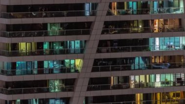 Apartman binasının parlayan pencerelerinin gece görüşü. Işıklı ve hareketli yüksek gökdelenler