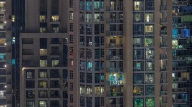Modern konut binalarındaki büyük parlayan pencereler gece saatlerinde, sıra sıra parlıyor..