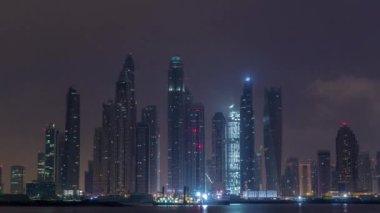 Gün geçiş timelapse Dubai şehir gece Palm Jumeirah Adası'içinde modern gökdelenler. Dubai, Birleşik Arap Emirlikleri. Dubai Yat Limanı ve sabah erken bulutlara Jbr