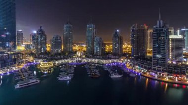 Dubai Yat Limanı bütün gece timelapse, Glittering ışıklar swithcing kapalı ve en yüksek gökdelenler sırasında. Işıklı kuleleri, yatlar ve arka plan üzerinde yolda trafik