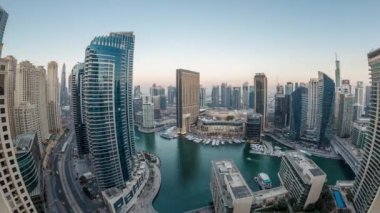 Dubai Marina 'nın gece gündüz aydınlanması. Hava geçiş panoramik zaman dilimi, BAE. Modern gökdelenler ve konut binaları. Yapay kanal şehrindeki alışveriş merkezinin yakınındaki yatlar ve tekneler.