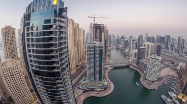 Dubai Marina gezinti güvertesi ve kanalı, gün batımından sonra Dubai, BAE 'de yüzen yat ve teknelerle panoramik hava manzaralı. Modern kuleler ve yoldaki trafik.