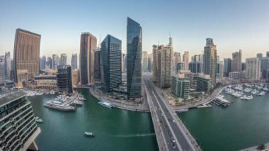 Dubai Marina gezinti güvertesi ve kanalı, gün batımından sonra Dubai, BAE 'de yüzen yat ve teknelerle panoramik hava manzaralı. Modern kuleler ve yoldaki trafik.