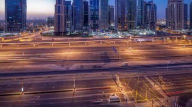 Jumeirah lakes hava görünümünü gün geçiş timelapse Şeyh zayed road ve metro hattı üzerinde trafik ile gecesine ışıklandırılmış gökdelenler ile kuleleri. Dubai Yat Limanı güneş doğmadan önce çatı görünümü